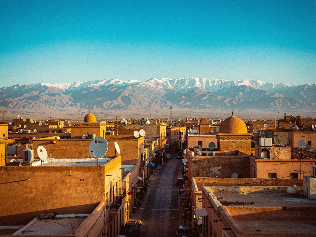 Toits ocre de la médina de Marrakech devant les montagnes enneigées de l'Atlas
